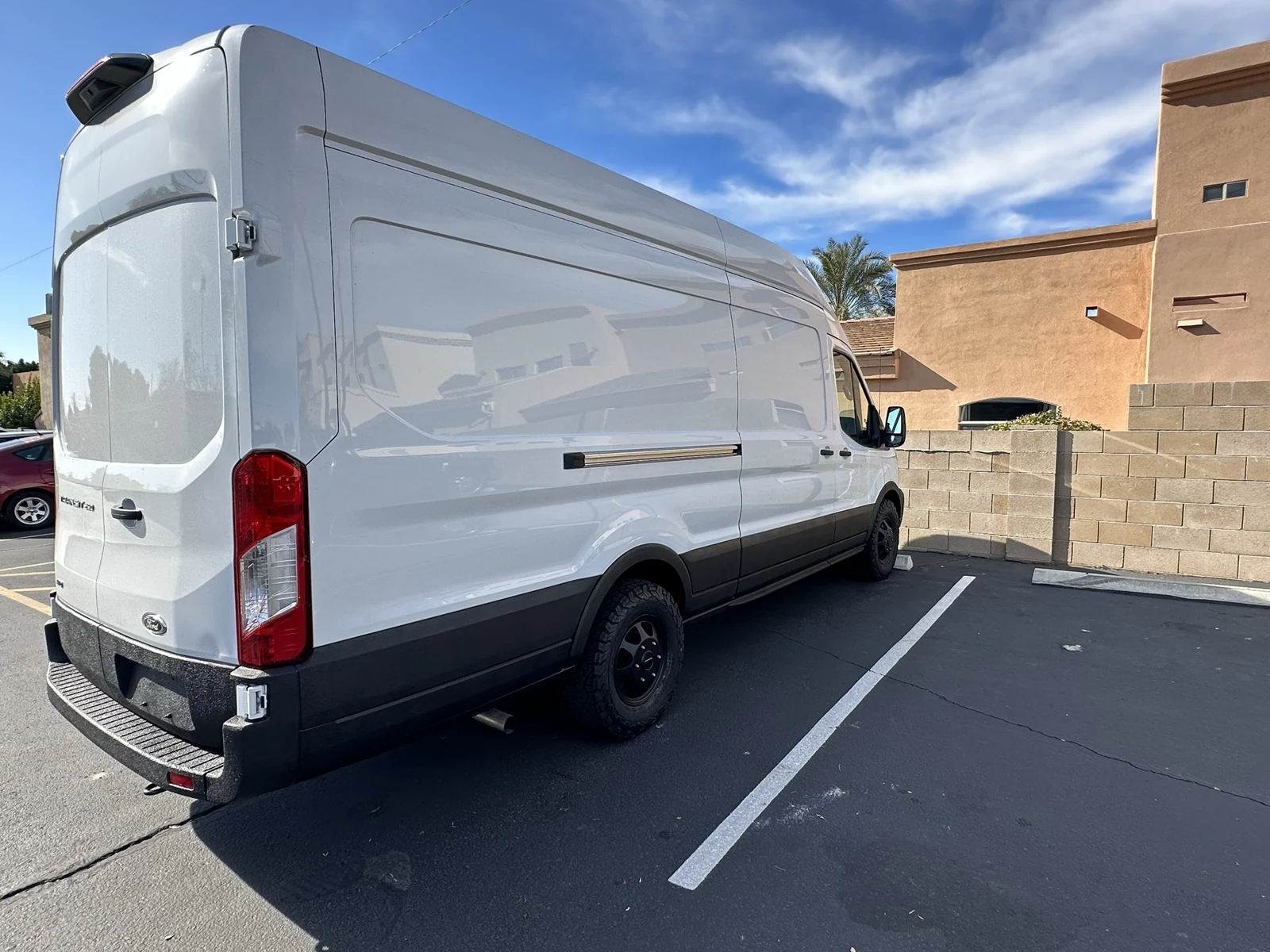 Rear passenger-side view of my white Transit with black lower trim and rear bumper.