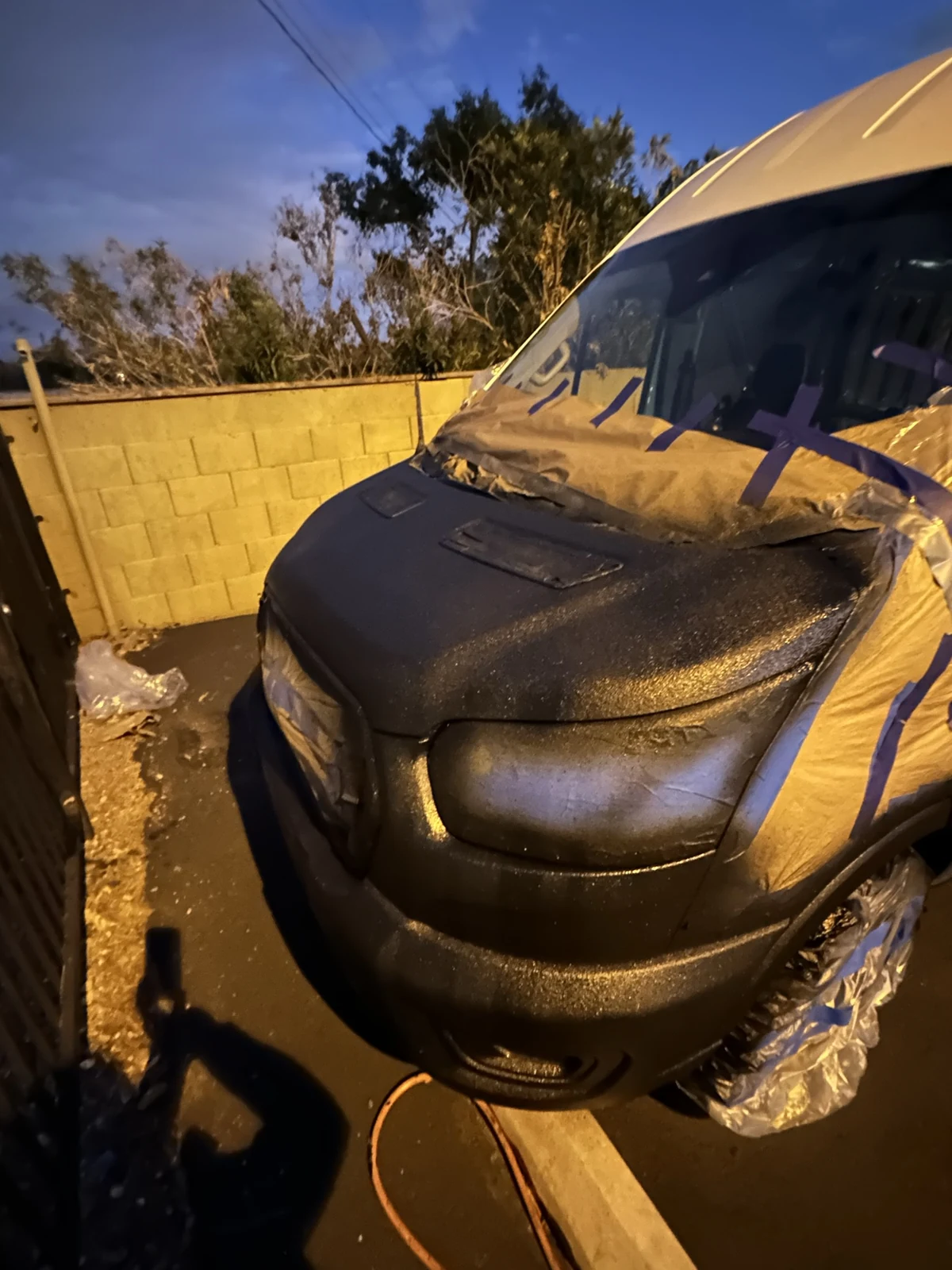 Black-coated Transit hood with the surrounding masking still in place at dusk.