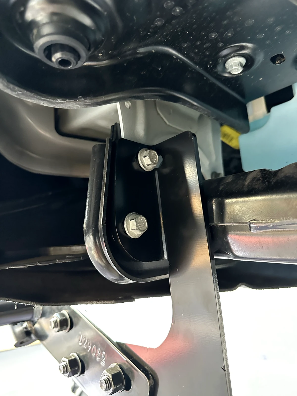 Underbody close-up of the attached black grille-guard bracket with two upper bolts and three lower fasteners