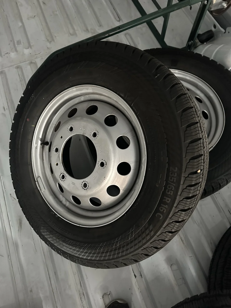 Removed original silver steel wheel and stock tire with the 235/65 R16C marking visible.