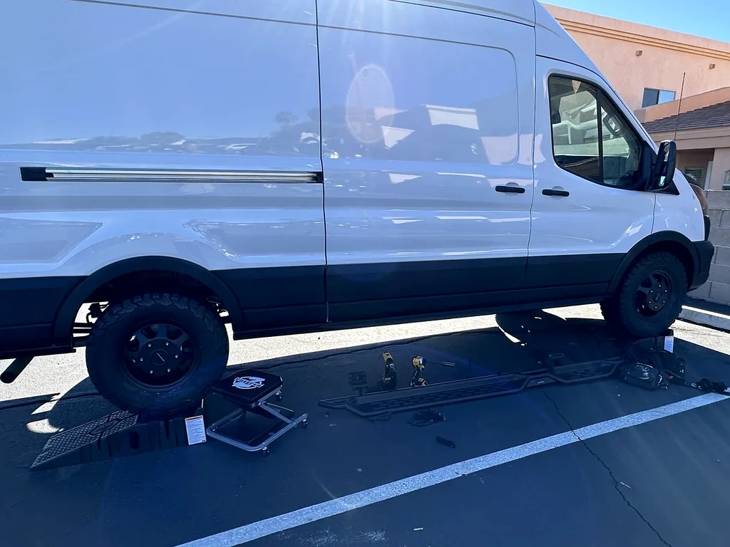My passenger-side running board, tools and creeper laid out beside the van.
