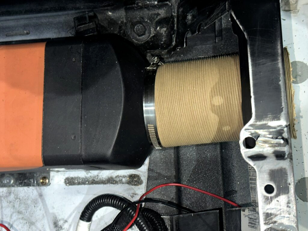 Top view of the heater and short warm-air duct inside the passenger-seat base.