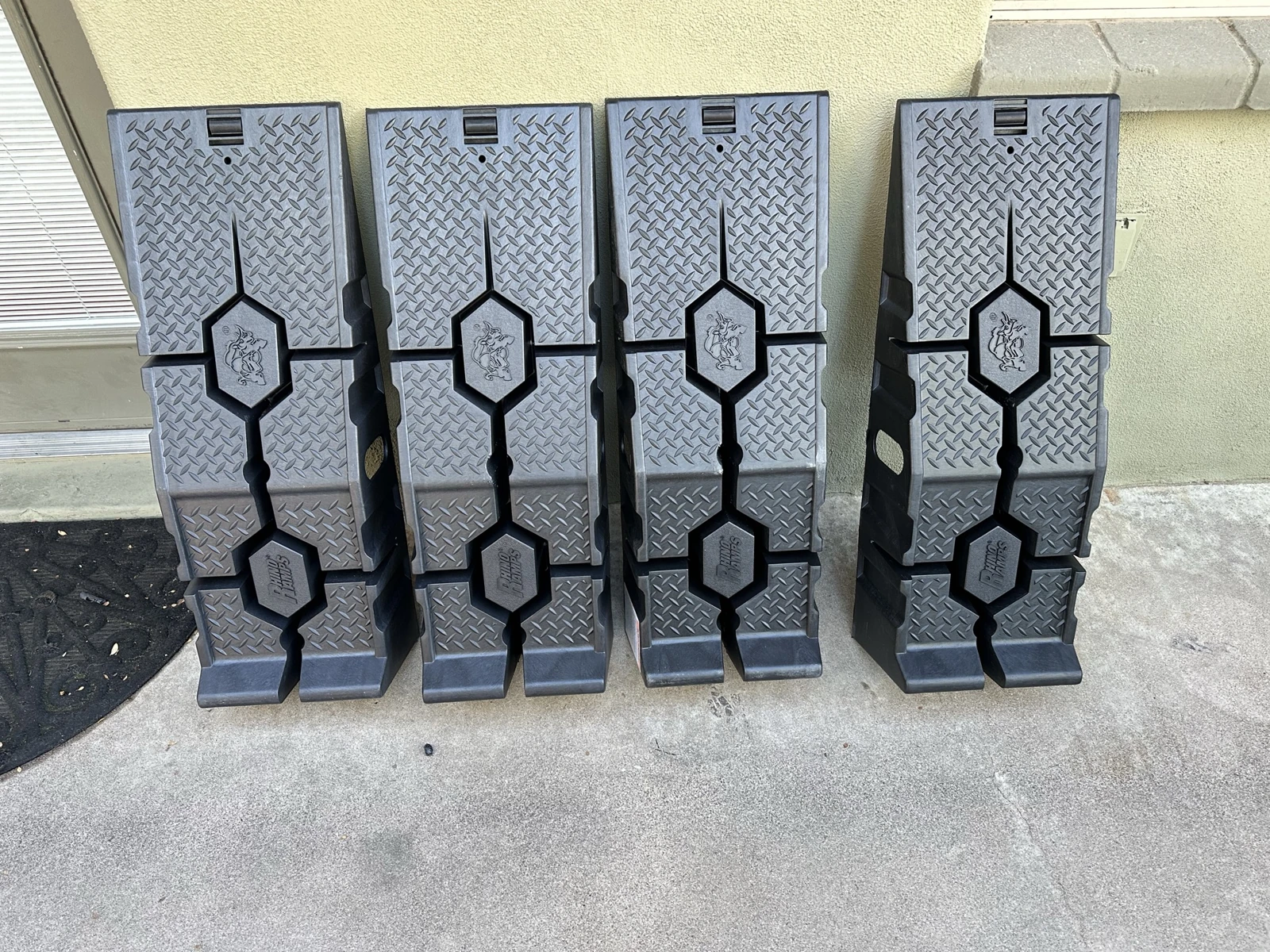 Four black molded ramps standing against a wall, with their tread faces visible.