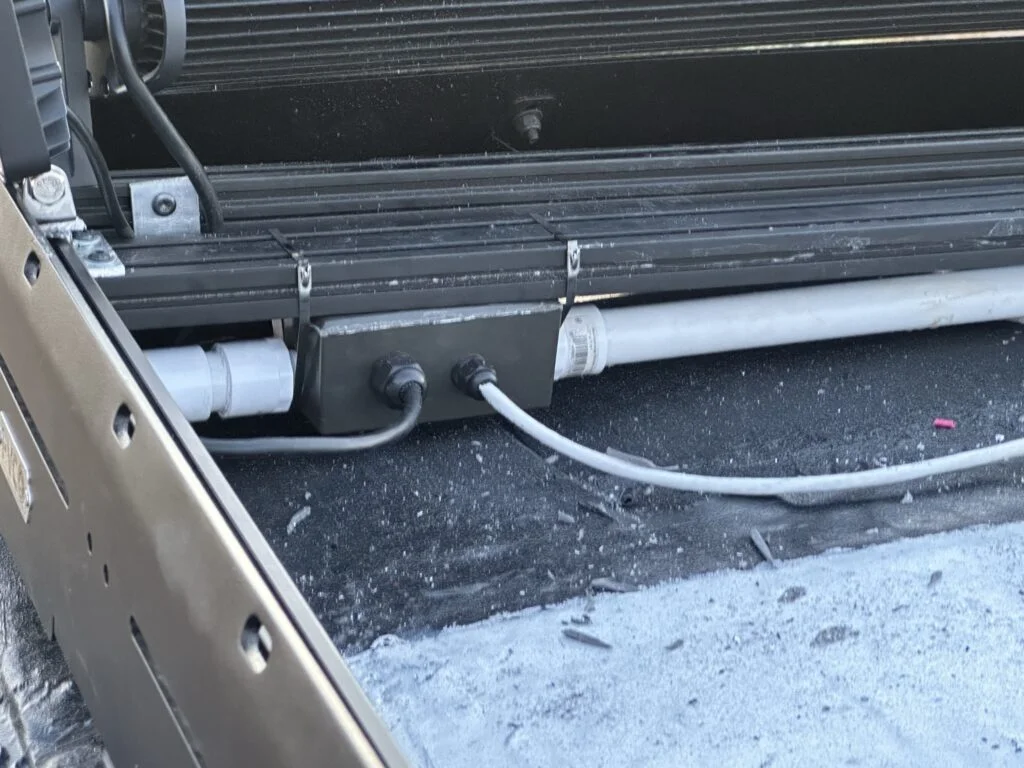 Cable-entry fittings and wires beside the roof conduit and junction box.
