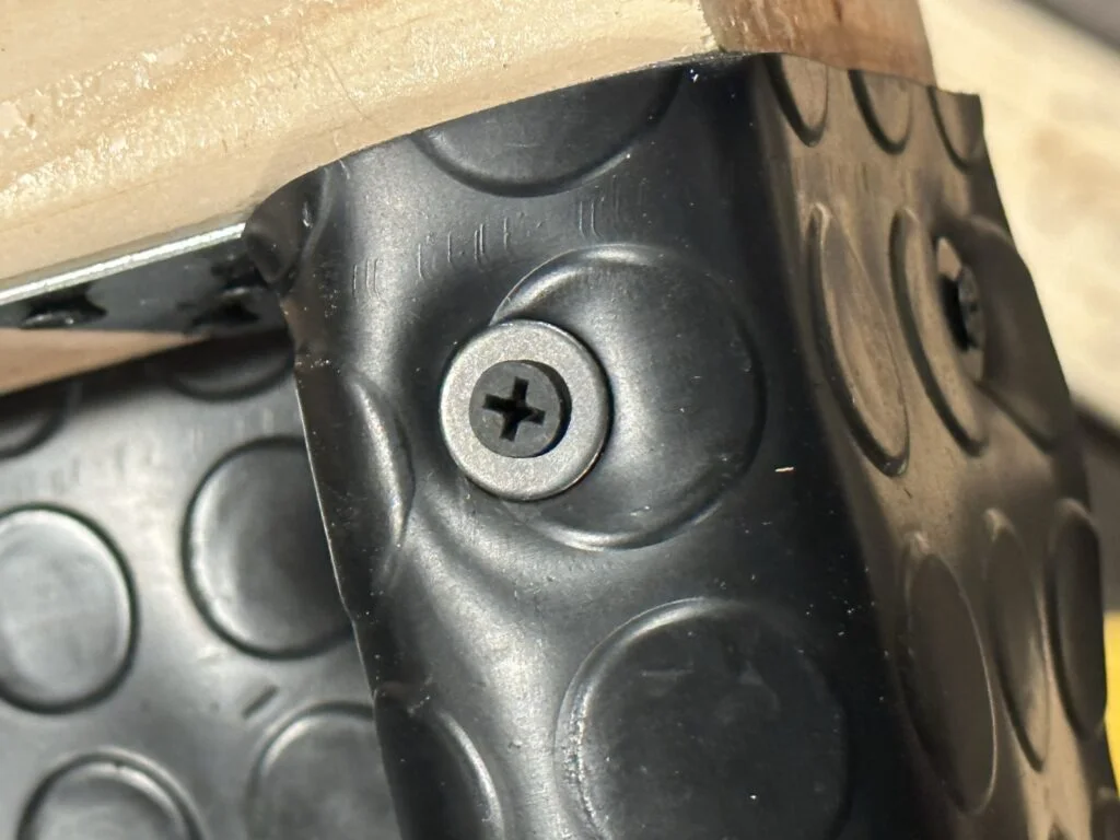 A screw and flat washer holding the rubber lining in my drawer assembly.