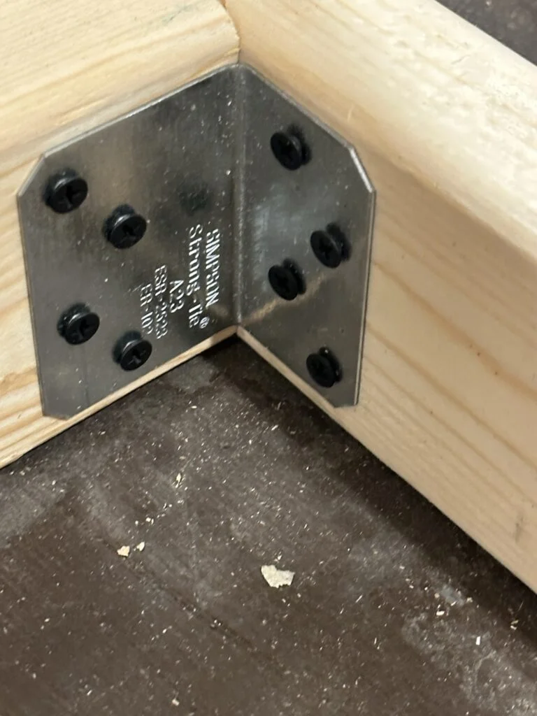 A steel angle bracket screwed inside a corner of my storage-bin drawer.