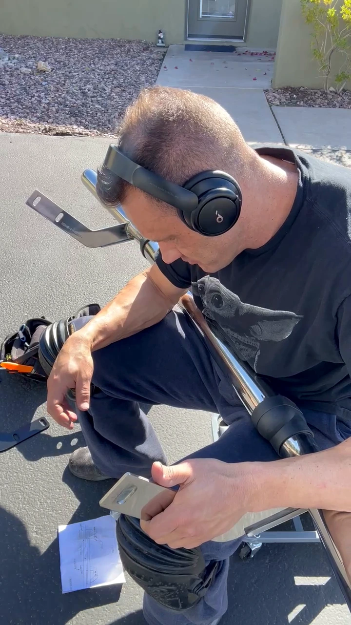 Steven Smith holding a bracket beside the chrome rear bumper guard during assembly